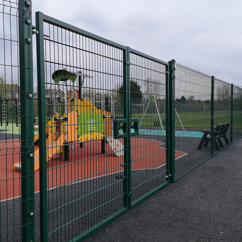 A green boundary perimeter fence with heavy duty gate providing security for a children's playground.