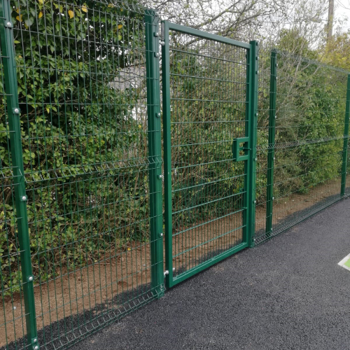 A large green heavy duty gate attached to a boundary fence at Lambeg children's park.